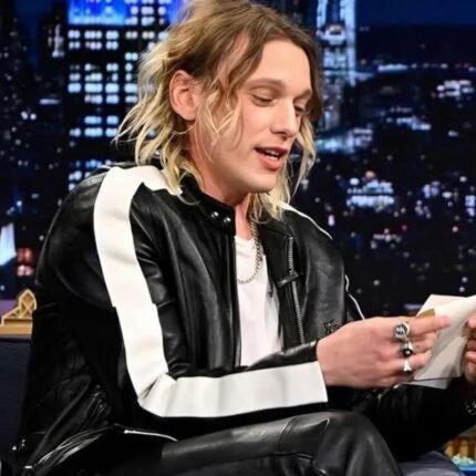 Jamie Campbell wearing a black leather jacket with white striped sleeves on The Tonight Show.