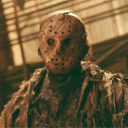 Masked horror character wearing distressed burlap-style costume in warm cinematic lighting