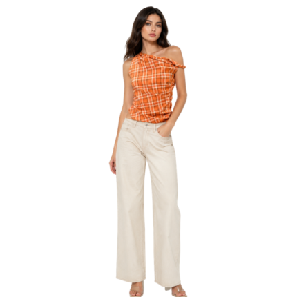 Woman wearing an orange plaid one-shoulder top with cream wide-leg jeans, front view.
