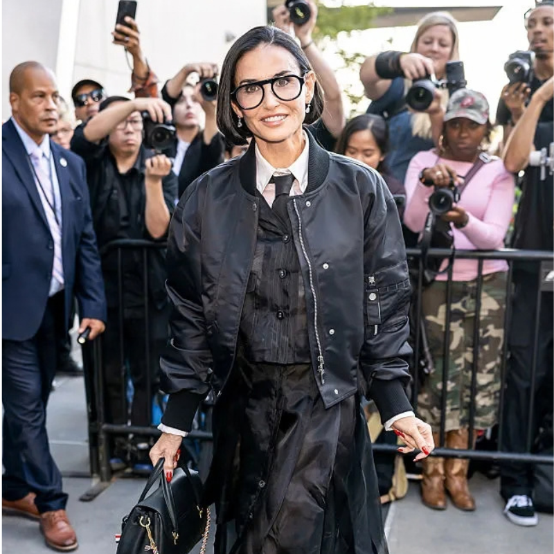demi-moore-thom-browne-spring-summer-2027-black-bomber-jacket Demi Moore wearing a black bomber jacket with rib-knit collar and cuffs