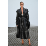 Rosie Black Trench Coat in real black leather with a long design, adjustable belt, notched lapel collar, and full-length sleeves.