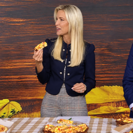 Ainsley Earhardt wearing a navy blue cropped blazer with gold-tone buttons and puff shoulders on Fox & Friends.