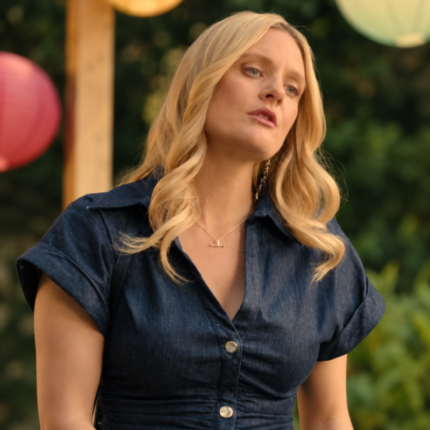 Woman wearing a dark indigo denim midi dress with a collared neckline, short sleeves, and silver-tone buttons