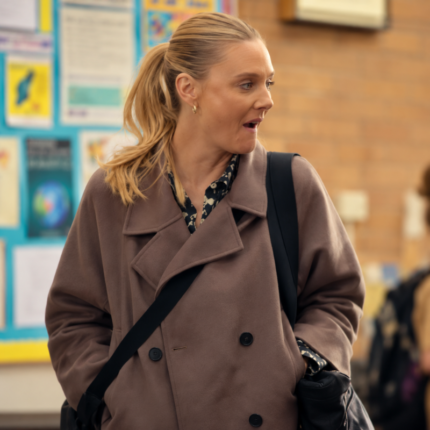 Woman wearing a taupe brown Beth-inspired trench jacket with wide lapels and black buttons