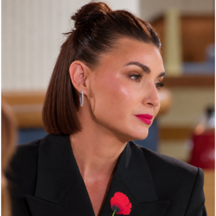 Woman wearing a black blazer with red floral embroidery on the lapel and a tailored neckline.