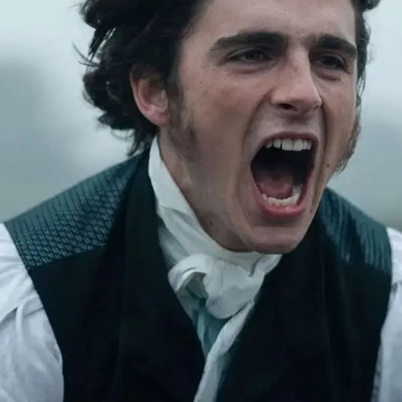 Jacob-Elordi-Wuthering-Heights-2026-Black-Vest Man in a white shirt, black vest, and neck scarf in a dramatic historical period-style scene.