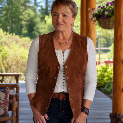 Woman wearing a brown suede vest over a white top with blue jeans in an outdoor setting.