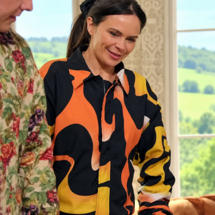 Woman wearing a black, orange, and yellow abstract print bomber jacket inspired by The Celebrity Traitors Season 2.