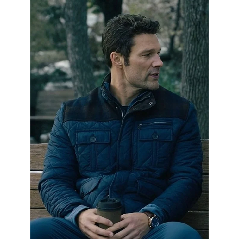 The-Way-to-You-Aaron-OConnell-Blue-Quilted-Jacket Aaron O’Connell sitting in a blue quilted jacket with dark shoulder panels and multiple front pockets.