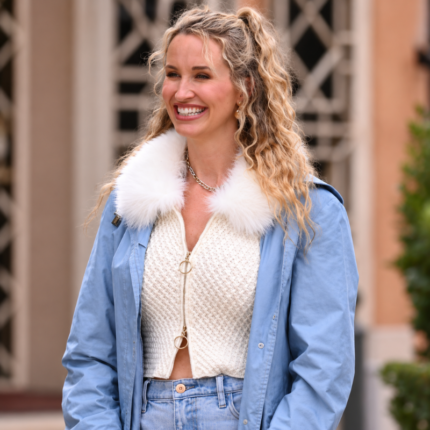 Woman wearing an ivory cropped knit jacket with a fluffy white faux fur collar and gold ring zippercuffs, gold ring zipper, and textured knit fabric